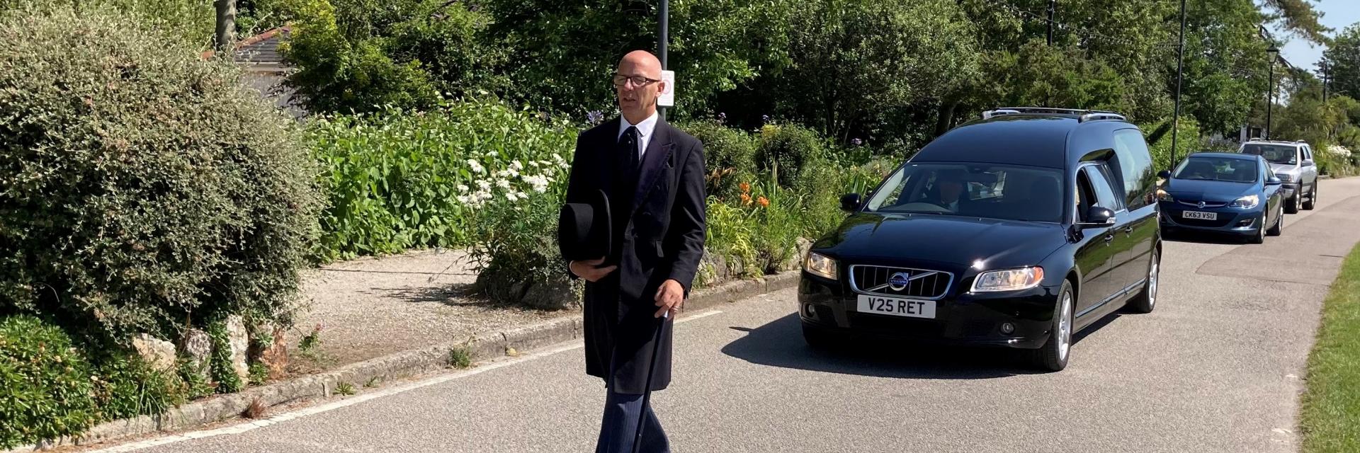 Saints funerals walking in front of a hearse